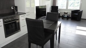 Une cuisine moderne avec des meubles blancs, une cuisinière noire et un coin repas comprenant une table et des chaises.