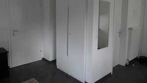 Une pièce avec une grande armoire, une porte dotée d’un miroir et un radiateur.