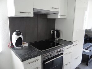 A modern kitchen with a black countertop, stainless steel appliances, and white cabinetry.