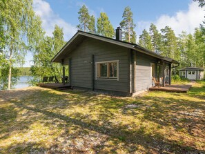 Une petite cabane avec une véranda, une terrasse et une vue sur un lac.