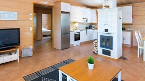 A modern log cabin interior with a kitchen, dining area, and a bedroom.