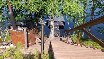 A wooden deck leading to a dock, a hot tub, and a chimney.