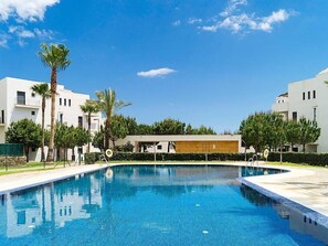 A swimming pool surrounded by modern buildings, palm trees, and a clear blue sky. - Apartment Alamar by Interhome (Mijas Costa)