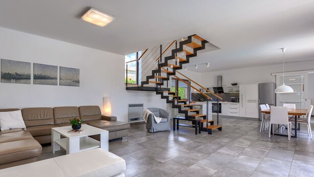 A modern living room with a staircase leading to a kitchen.