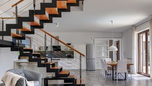 A modern living space with a staircase, a dining area, and a kitchen.