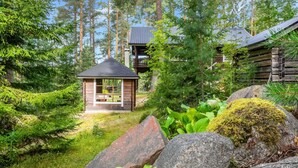 A cabin with a small wooden structure, surrounded by dense forest and large rocks.