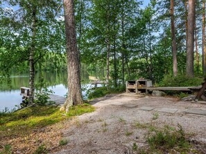 Un camping paisible au bord du lac, avec un banc en bois, une table de pique-nique et un petit abri.
