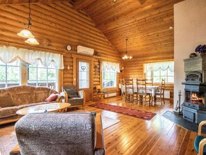 L’intérieur d’une cabane en rondins, avec une cheminée, des meubles en bois et un coin repas.