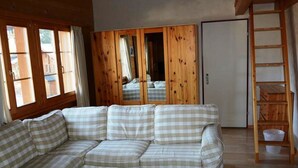 A cozy living room with a checkered sofa, wooden walls, and a large mirror reflecting the room.