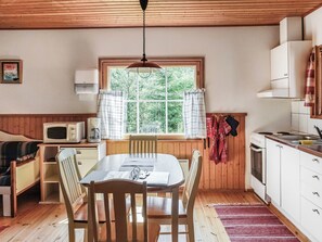 A cozy kitchen with wooden cabinets, a dining table, and a window with curtains. - Kalatiira 3 by Interhome (Parainen)