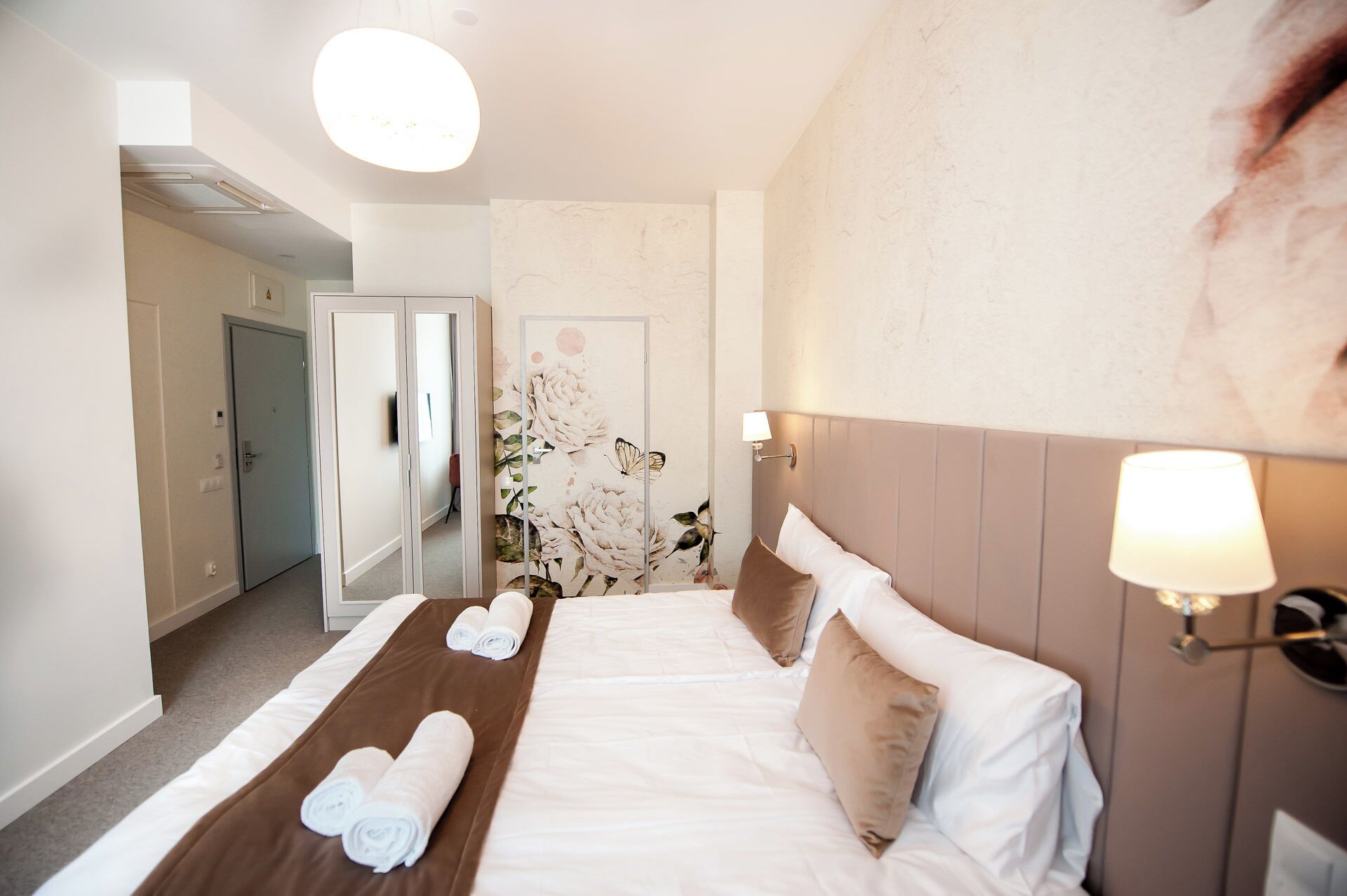 Een hotelkamer met een bed, een spiegel en een bloemen behangen muur.