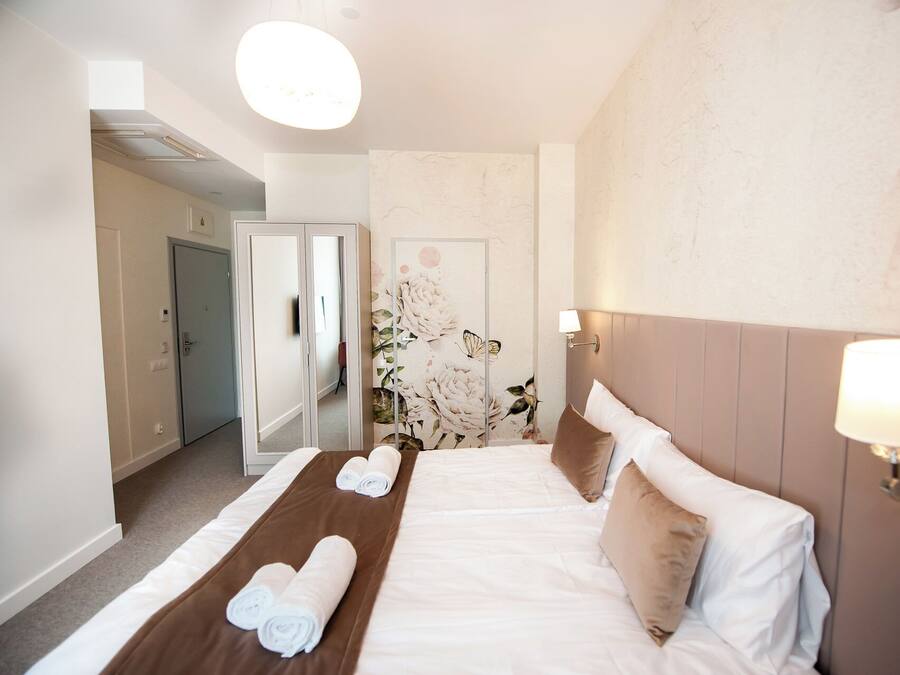Een hotelkamer met een bed, een spiegel en een bloemen behangen muur.