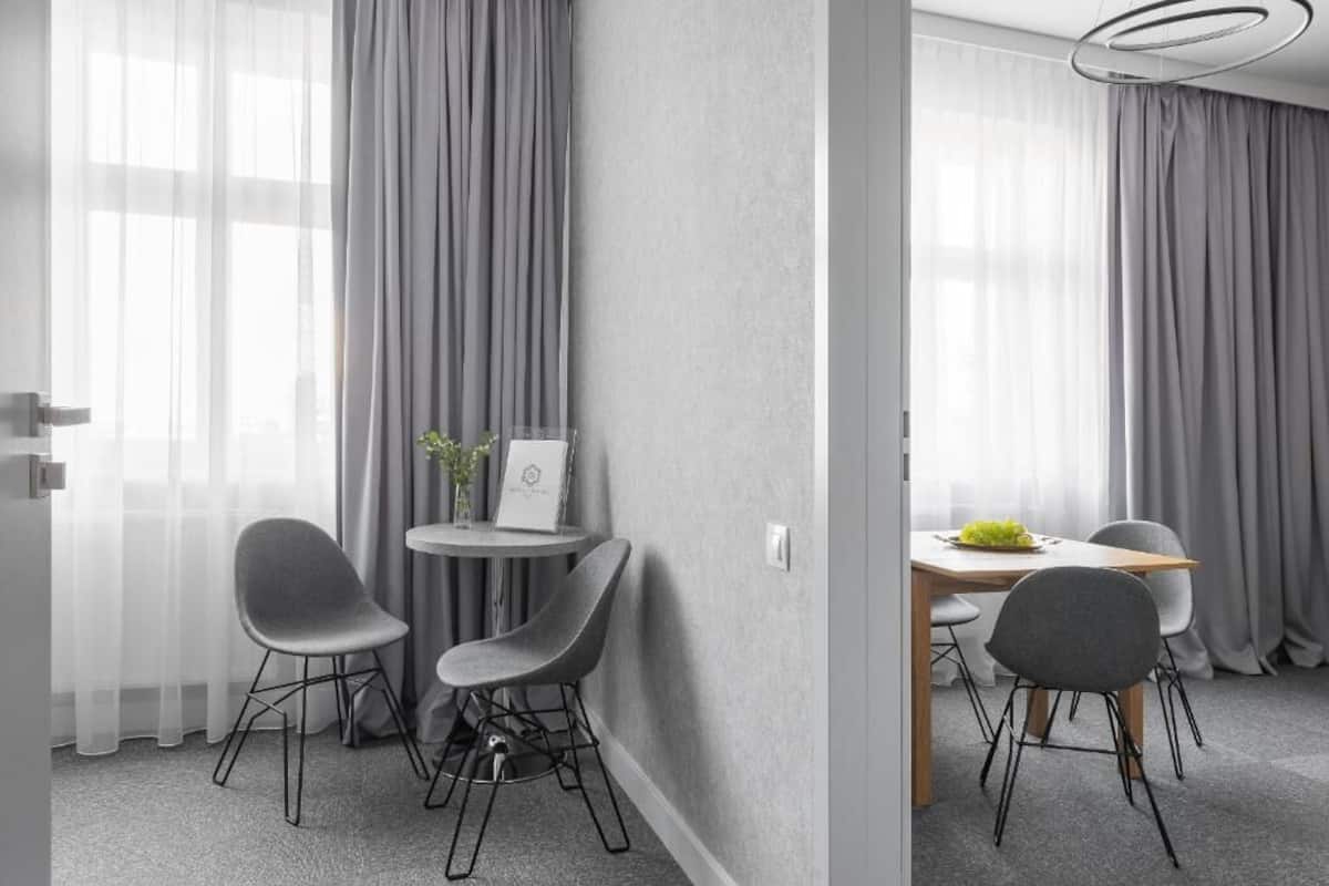A modern room with grey walls, a round table with four chairs, and a small side table with a plant and a framed picture.