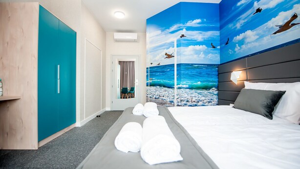 A hotel room with a bed, a bathroom, and a view of the ocean with birds. - Hotel Gdynia Boutique (Gdynia)