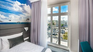 A hotel room with a bed, a view of the city through large windows, and a mural of the sky and sea on the wall. - Hotel Gdynia Boutique (Gdynia)