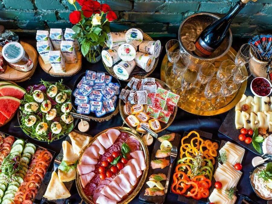 Diversa selección de alimentos y bebidas, como quesos, embutidos y aperitivos, dispuesta sobre una mesa.