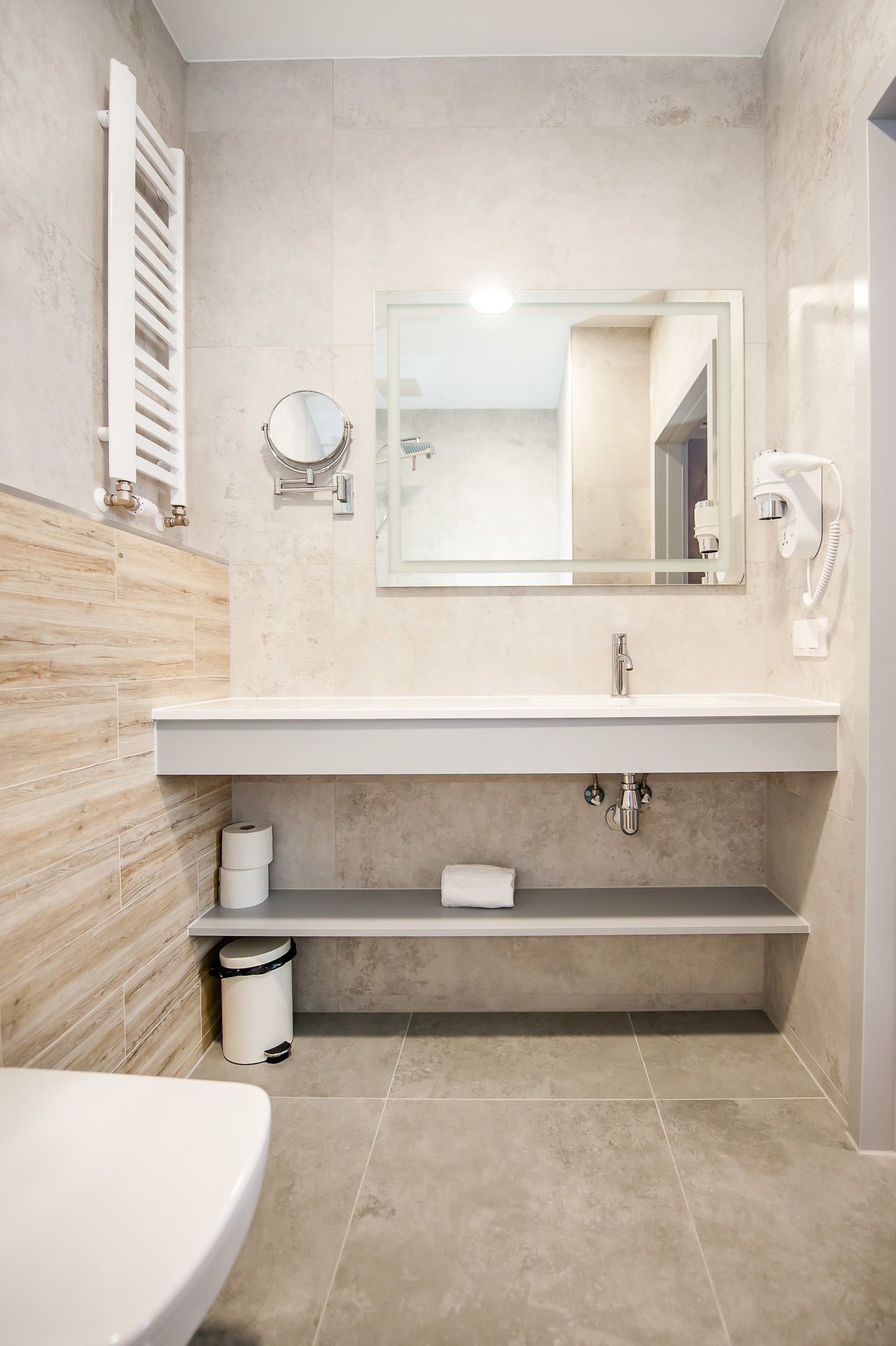 Un baño moderno con lavamanos, espejo y perchero blancos.