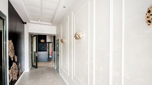 A hallway with a modern design, featuring a light-colored floor, white walls with decorative moldings, and a ceiling with recessed lighting. - Hotel Gdynia Boutique (Gdynia)
