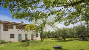 A white building with a tiled roof, a small garden with a trampoline, and a birdhouse. - Oliveto by Interhome (Vinci)