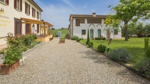 A building with a gravel driveway leading to a covered patio area. - Oliveto by Interhome (Vinci)