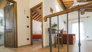 A spacious living area with a wooden floor, a dining table with chairs, a sofa, and a staircase with a wooden railing. - Oliveto by Interhome (Vinci)
