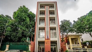 Un edificio de varios pisos con una entrada central, balcones en cada planta y una bandera en la parte superior.
