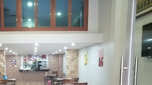 Comedor con techo alto, paredes de ladrillo y una barra central con menú a la vista.