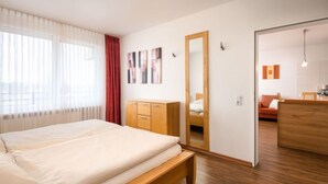 Una camera da letto moderna con un letto, un'armadio in legno e uno specchio che riflette un'altra stanza.