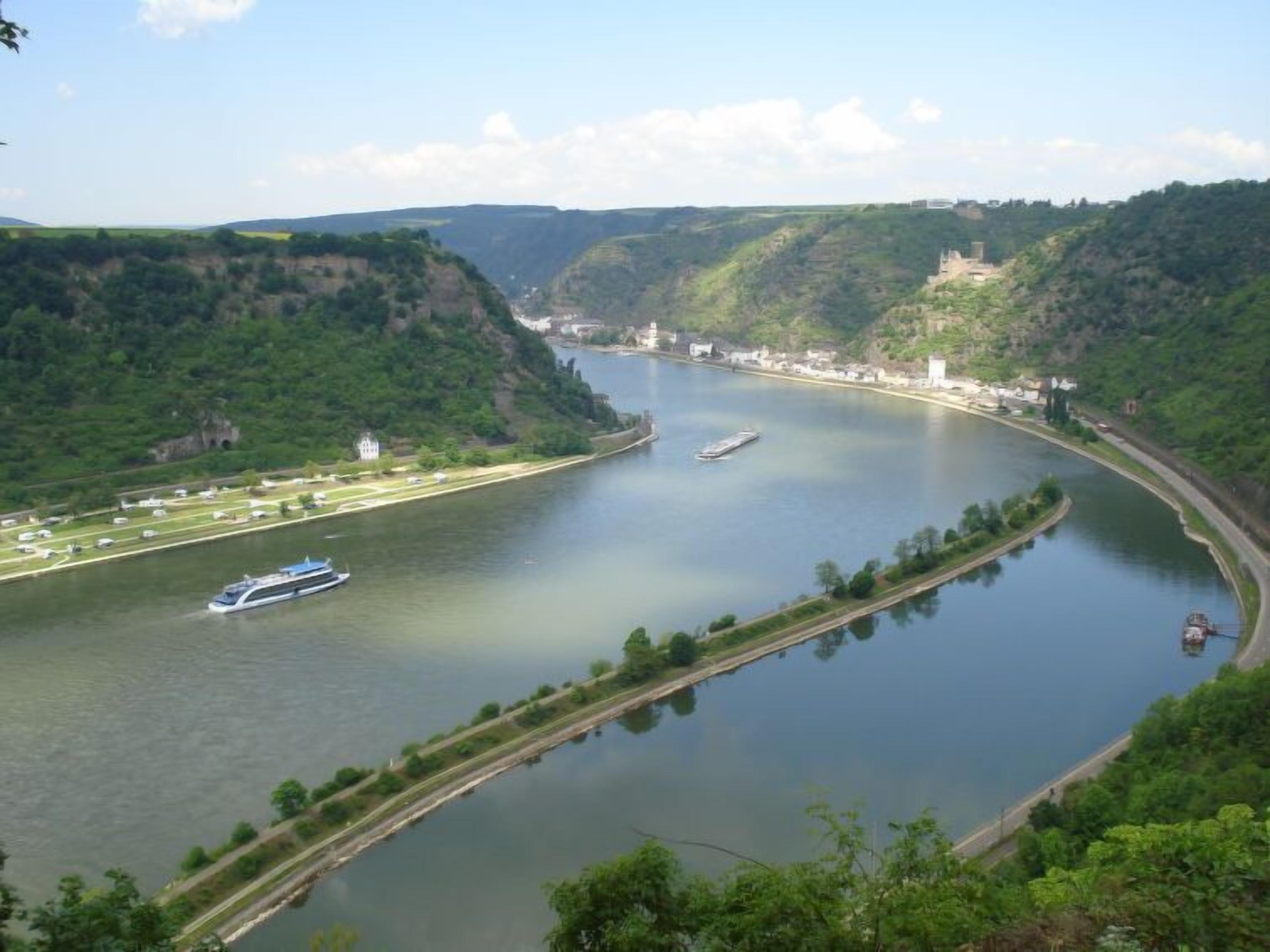 A river with a boat, a bridge, and a castle-like structure on a hill.