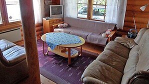 A cozy cabin interior with a sofa, a small table, and a television.