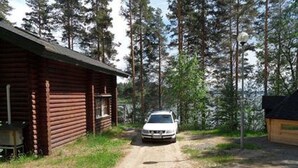 A cabin with a dirt path leading to it, surrounded by tall trees.