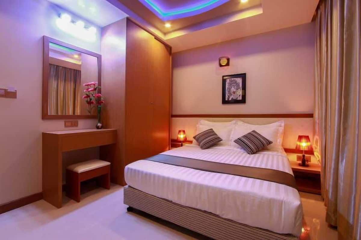 A hotel room with a large bed, bedside lamps, a vanity with a mirror, and a framed picture on the wall.
