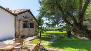 A stone building with a tiled roof, outdoor seating, and a well-maintained lawn. - Vacation home Moira by Interhome (Umag)