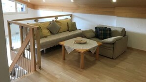 A cozy living room with a wooden ceiling, a sofa, a small table, and a staircase. - Disentiserhof Hönig by Interhome (Disentis)