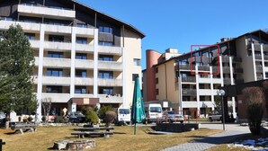 A multi-story building with balconies, a parking area, and a small park with benches. - Disentiserhof Hönig by Interhome (Disentis)