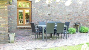 An outdoor patio with a brick wall, a window, and a table with chairs. - Apartment Krause by Interhome (Norden)
