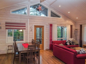 A cozy interior with a dining area, a red sofa, and a large window. - Teerenpesä by Interhome (Nilsiä)