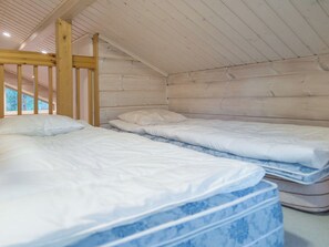 A room with two beds, wooden beams, and a sloped ceiling. - Teerenpesä by Interhome (Nilsiä)