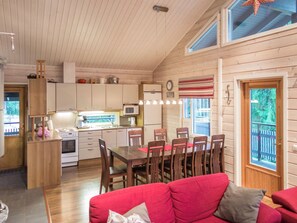 A cozy cabin interior with a dining area, kitchen, and a red couch. - Teerenpesä by Interhome (Nilsiä)