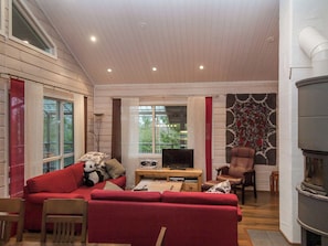 A cozy living room with a red sofa, a television, and a fireplace.