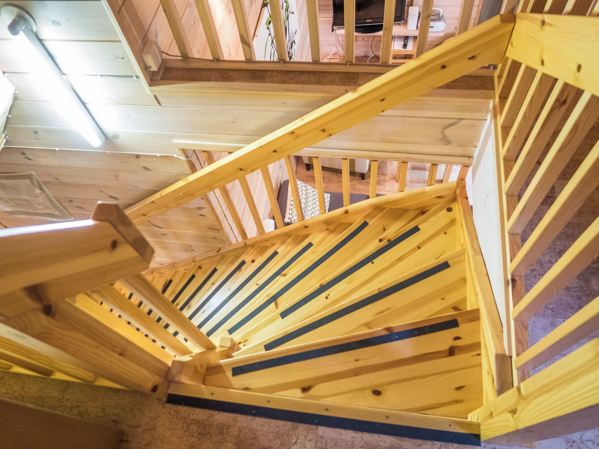 A wooden staircase with a handrail and a carpeted landing area.