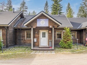 Un bâtiment en bois avec une enseigne indiquant « VILLA KOIRA » et un petit porche doté d’une porte.