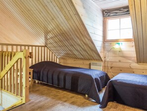 Une petite pièce chaleureuse, avec deux lits, des murs en bois, un plafond en pente et une fenêtre donnant sur un beau paysage.