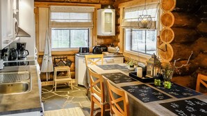 L’intérieur d’un chalet rustique comprend une cuisine, un coin repas et une grande fenêtre.