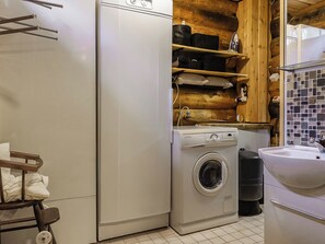 Pequeña lavandería con lavadora, secadora y lavabo.