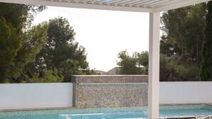Ein Poolbereich mit Liegestühlen, einer gefliesten Wand und Blick auf den Pool.