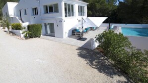 Ein modernes, zweistöckiges Haus mit Swimmingpool, Sitzgelegenheiten im Freien und einem gepflegten Garten.