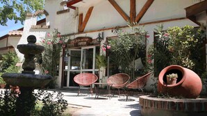 A courtyard with a fountain, wicker chairs, and potted plants. - Hotel Jardín del Lago (Las Cabras)