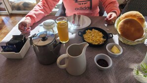 A dining table with breakfast items including eggs, toast, and a jug of juice. - Hotel Jardín del Lago (Las Cabras)