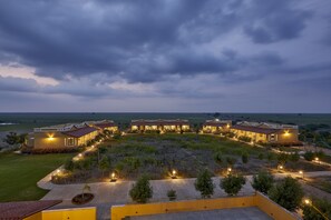 A resort with multiple buildings, a well-maintained lawn, and a large open area with pathways and trees. - Blackbuck Safari Lodge Velavadar (Bhavnagar)